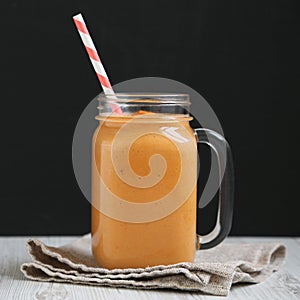 Homemade pumpkin smoothie in a glass jar mug, side view. Close-up