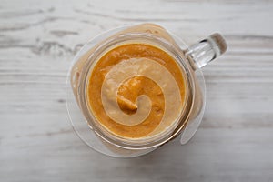 Homemade pumpkin smoothie in a glass jar on a white wooden background. Flat lay, overhead, from above. Close-up