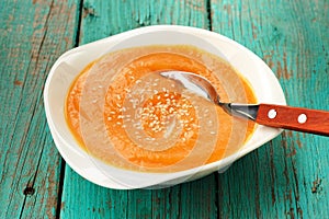 Homemade pumpkin soup puree with sesame seeds on turquoise table