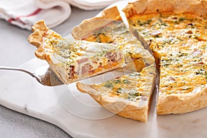 Homemade quiche with ham and cheese cut on the table