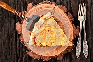 Homemade quiche with leek, ham and cheese on wooden background.