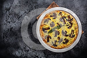 Homemade quiche pie with mushrooms and cheese on dark background, Savory tart pie with mushrooms. Traditional french pie Quiche