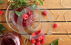 Homemade raspberry jam in glass jars on wooden table top