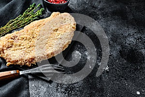 Homemade raw breaded German Weiner Schnitzel. Black background. Top view. Copy space