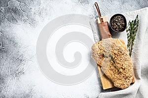 Homemade raw breaded German Weiner Schnitzel. Gray background. Top view. Copy space