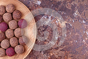 Homemade Raw Vegan Cacao Energy Balls on Wooden Plate on Brown Marble Background