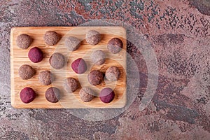 Homemade Raw Vegan Cacao Energy Balls on Wooden Tray on Brown Marble Background