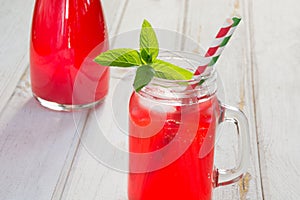 Homemade red currant lemonade in a mason jar with decor on ligth wooden table.