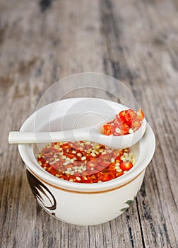 Homemade red Thai sauce with chopped chilli on wooden table at local cafe in Ching Mai, Norther Thailand. Traditional spicy food c