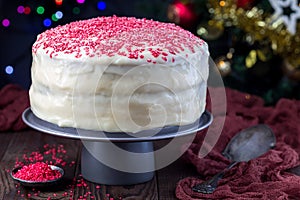 Homemade red velvet cake with cream cheese frosting and red sugar decoration, low key photo with boke lights and christmas