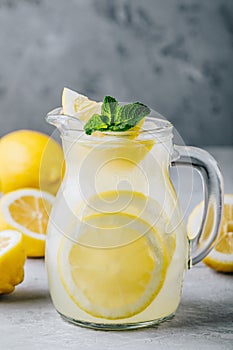 Homemade refreshing summer lemonade drink with lemon slices, ginger and ice