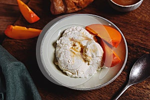Homemade ricotta cheese or cheese curd served with fresh persimmon and honey
