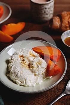 Homemade ricotta cheese or cheese curd served with fresh persimmon and honey and croissante