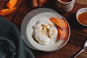 Homemade ricotta cheese or cheese curd served with fresh persimmon and honey and croissante