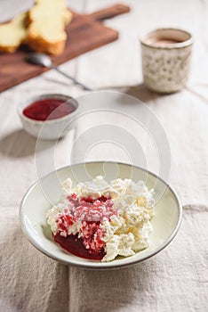 Homemade ricotta soft cheese or cottage cheese served with raspberry jam and fresh bread