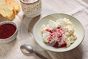 Homemade ricotta soft cheese or cottage cheese served with raspberry jam and fresh bread