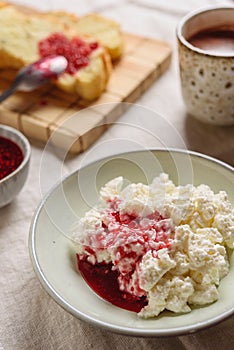 Homemade ricotta soft cheese or cottage cheese served with raspberry jam and fresh bread