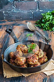 Homemade roasted beef meatballs in cast-iron pan on wooden table in kitchen