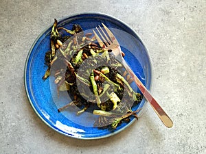 Homemade roasted broccoli with pine nuts served on blue plate