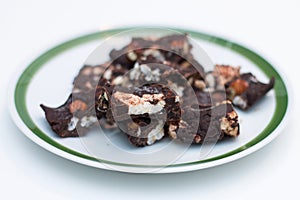 Homemade Rocky road chocolate on white plate with green trim on