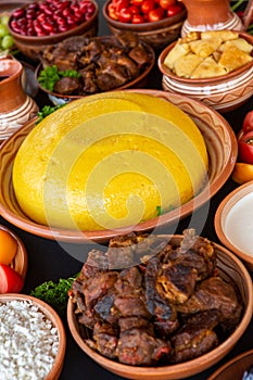 Homemade Romanian Food with polenta, meat, cheese and vegetables. Delicious corn porridge in clay dishes.