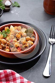 Homemade Ropa vieja, typical Canarian dish of chickpeas stew with chicken and potatoes in a earthenware casserole on marble table photo