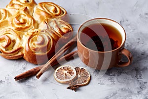 Homemade rose bread, cup of tea, dried citrus and spicies on white textured background, close-up, shallow depth of field