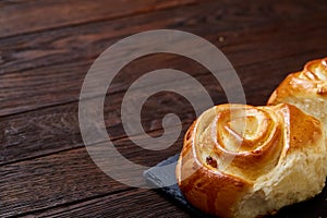 Homemade rose buns on stony cutting board over rustic vintage background, close-up, shallow depth of field