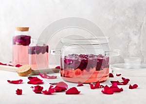 Homemade rose syrup in a glass pot with pink organic petals for making lemonade, cocktail, sweet summer drinks.