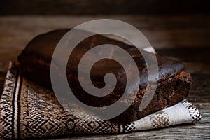 Homemade rustic bread on a kitchen napkin, on wooden background.