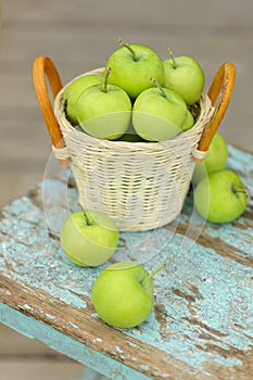 Homemade rustic green apples in a basket on an old stool.