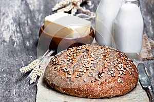 Homemade rye bread on baking paper and bottles of milk on woode