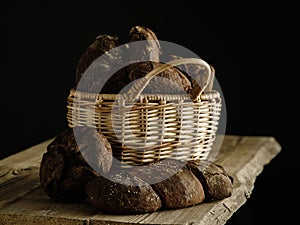 Homemade rye bread in a basket on a dark background.