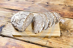 Homemade rye bread with sunflower and pumpkin seeds on wooden background. Side view.
