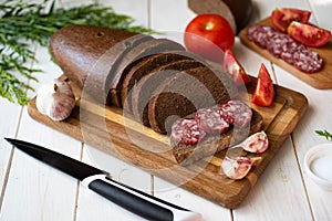 Homemade rye bread on a wooden board. Slices of rye bread on a platter. Sausage sandwich