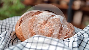 Homemade rye loaf on natural linen towel in home kitchen, closeup view, fresh bread spinning around