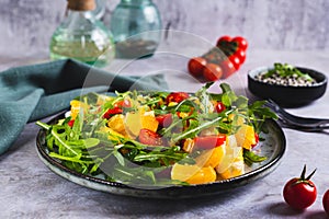 Homemade salad of orange, cherry tomatoes and arugula on a plate on the table