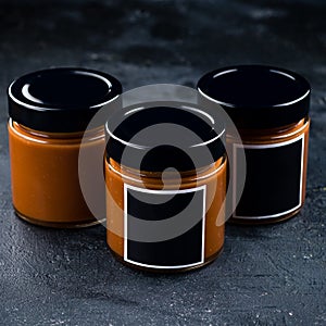 Homemade salted caramel sauce in a vintage jar on a dark slate, stone or concrete background.