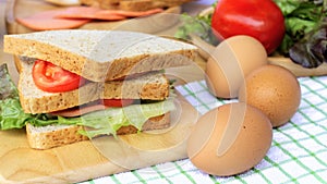 Homemade sandwich breakfast preparing. Close up whole wheat sandwich bread with slice tomatoes and lettuce stacked on wooden cutti