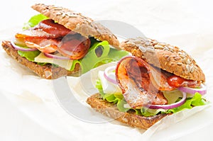 Homemade sandwich with ham bacon, cheese, lettuce and onion on white background