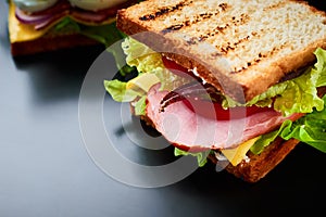Homemade sandwich with lettuce and ham on a black background, close up