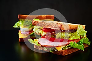 Homemade sandwich with lettuce and ham on a black background, close up