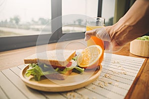 Homemade sandwich with orange juice on wood table