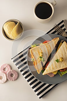 Homemade sandwich. Toasted double panini with ham, cheese fresh vegetables. Snack at work or lunch. Light background