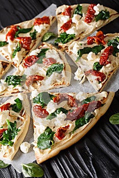 Homemade sandwiches with hummus, sun-dried tomatoes, spinach and goat cheese close-up. vertical