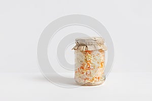 Homemade sauerkraut. Fermented food. Sauerkraut with carrots in a glass jar on a white wooden background photo