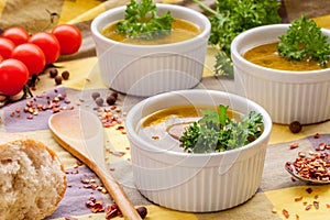 Homemade sausage soup with parsley in white ramekin bowls