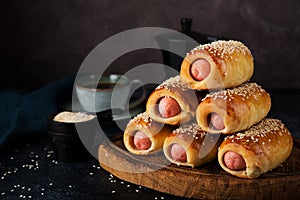 Homemade sausages baked in dough  pigs in blankets on a dark background, fast street food, close-up