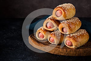 Homemade sausages baked in dough  pigs in blankets on a dark background, fast street food, close-up