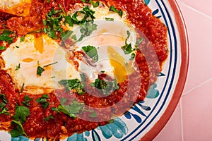 Homemade shakshuka breakfast topped with fresh herb leaves and garnished with flatbread